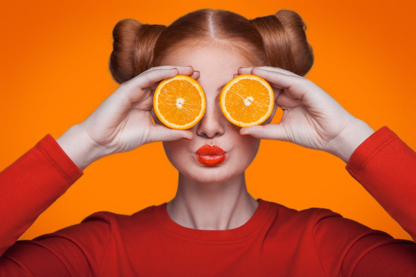 Young beautiful fashion model with orange. studio shot.